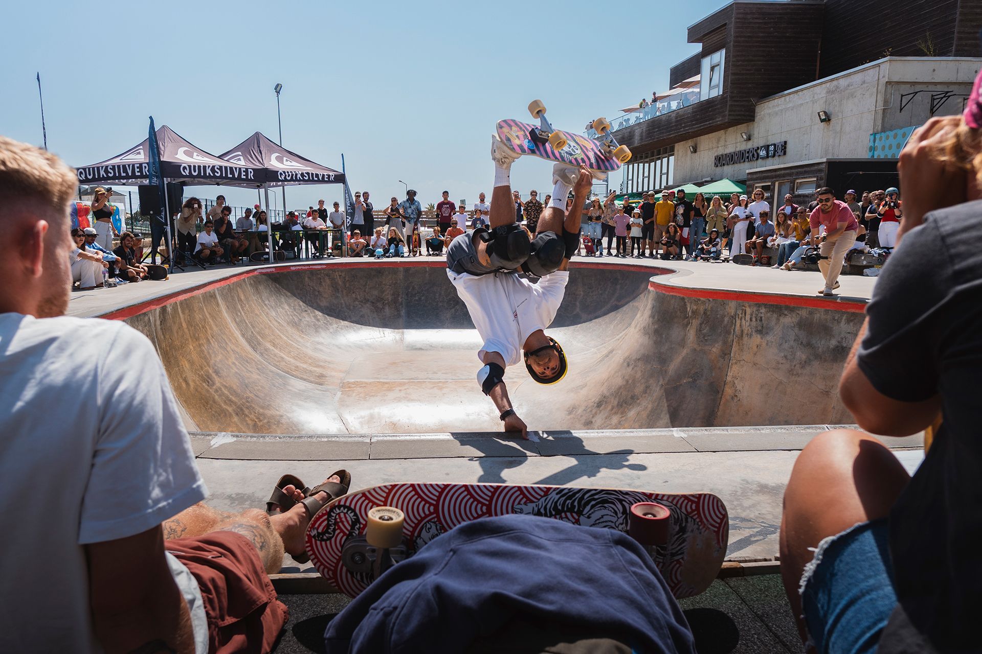 Skater blasting an inverted air out of a bowl at a packed summer contest.